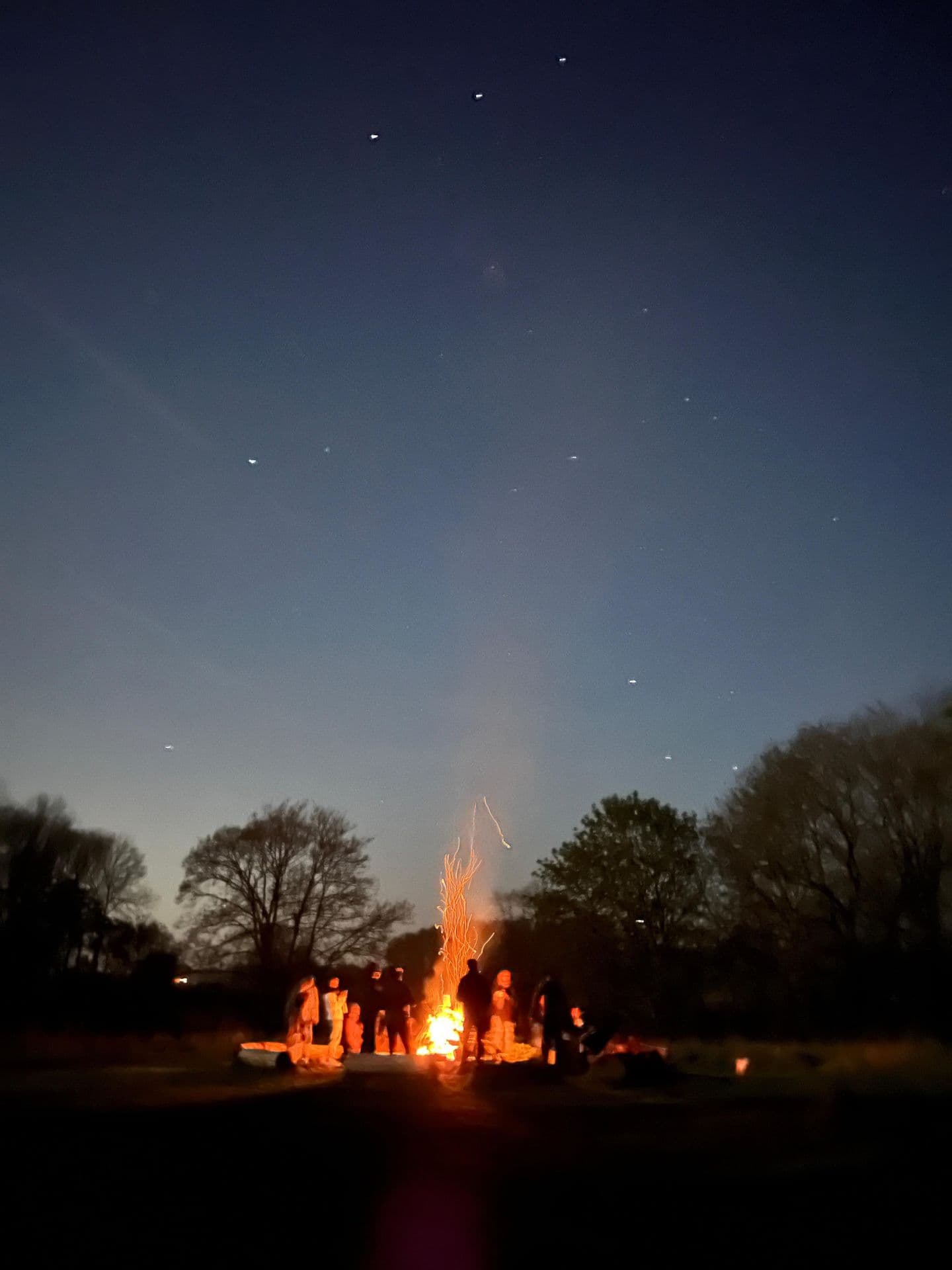 Bonfire under a dusk sky with stars visible